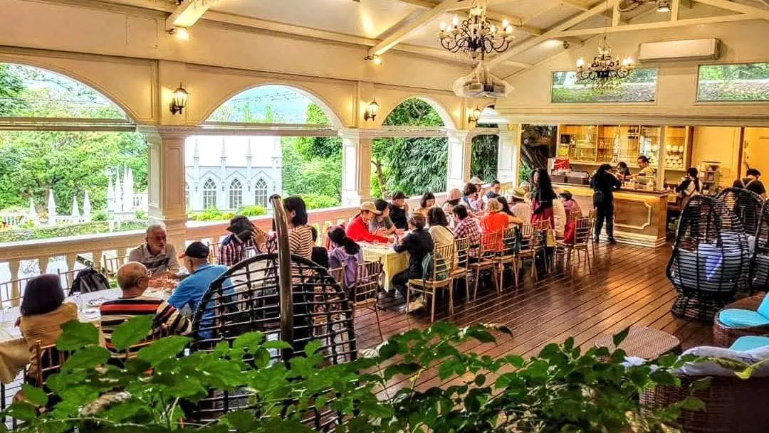 真愛桃花源庭園餐廳露台用餐區,拱形廊柱外可見哥德式教堂與陽明山山景,長桌聚餐座無虛席